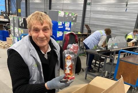 Een medewerker van Bewel poseert met een van de cadeaupakketten die hij hielp verpakken voor Sinterklaas.